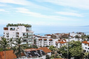 Ein Küstenwohngebiet mit weißen Gebäuden, Palmen und Blick auf das Meer.