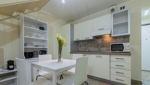 A modern kitchen with white cabinetry, a dining table with chairs, a coffee machine, and a microwave. - Loft San Carlo by Wonderful Italy (Turin)
