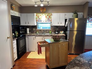 A kitchen with white cabinets, a stainless steel refrigerator, a microwave, and a blender. - Beautiful 2-bedroom mobile home in quaint Largo, close to beaches (Largo)
