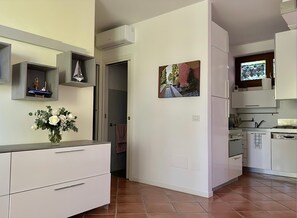 Una cucina moderna con mobili bianchi, forno integrato e una piccola isola con lavandino.