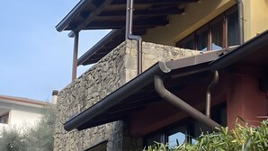 Un edificio con fachada de piedra, un balcón con barandilla de metal y una estructura de techo de madera.