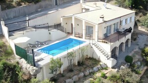Una casa de dos pisos con piscina, zona de estar exterior y jardín.