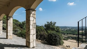 Una estructura de piedra con arcos, un camino de grava y vistas a un paisaje verde con colinas.