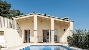 Un edificio de dos pisos con piscina, un patio cubierto y una escalera que lleva al nivel superior.