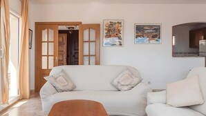 Una sala de estar con un sofá, una puerta de madera y dos cuadros en la pared.