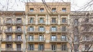 A multi-story building with balconies, a storefront at the ground level, and a sign indicating a business. - Premium 3-Bedroom Retreat in the Heart of Barcelona (Barcelona)