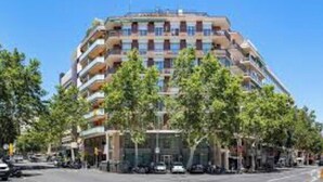A multi-story building with balconies, a parking lot, and trees in front. - Premium 3-Bedroom Retreat in the Heart of Barcelona (Barcelona)