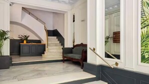 A grand staircase leading to a landing with a sofa and a potted plant. - Premium 3-Bedroom Retreat in the Heart of Barcelona (Barcelona)