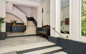 Eine imposante Treppe führt zu einer Empfangshalle mit einer Couch und einem Blumentopf.