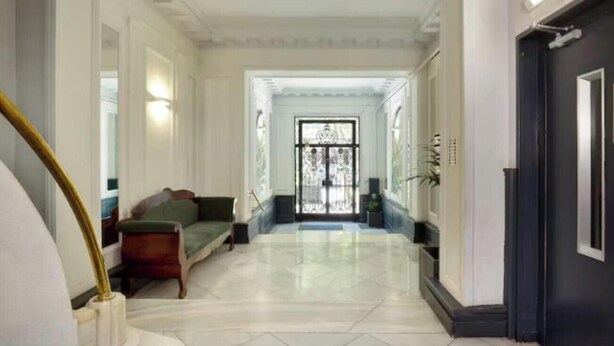 A hallway with a staircase, a green sofa, and a black door. - Premium 3-Bedroom Retreat in the Heart of Barcelona (Barcelona)
