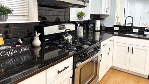 Cozinha moderna com fogão a gás, micro-ondas e armários brancos.