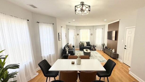 Uma sala de estar moderna com área de jantar, sofá, televisão e uma planta.