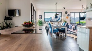 A modern kitchen with a wooden countertop, a dining area with blue chairs, and a view of the outdoors through large windows. - Villa with jacuzzi, 5 bedrooms - ideal for families (Inzinzac-Lochrist)