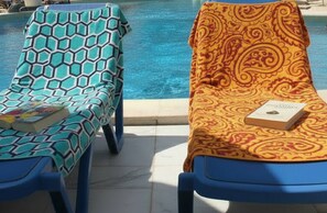 Two sun loungers by a pool with patterned covers and a book on one. - Apartment Near the Beach with Ocean View, Just Steps Away (Costa Adeje)