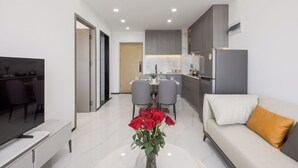 A modern living room with a sofa, a TV, a dining area, and a kitchen. - Pinnacle Moments Residence (Phnom Penh)