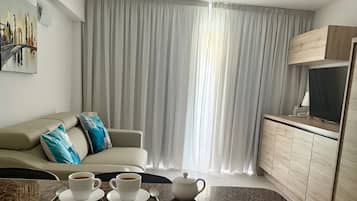 A living room with a sofa, two cups of coffee, a table, and a TV.