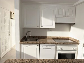 A compact kitchen with white cabinetry, a stainless steel sink, a dishwasher, and an oven. - Sant’Eugenio Basso. Extraordinary Penthouse near the Beaches with Breathtaking Ocean View (San Eugenio Alto)