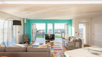 A modern living room with a sofa, a coffee table, a TV, and a fireplace.