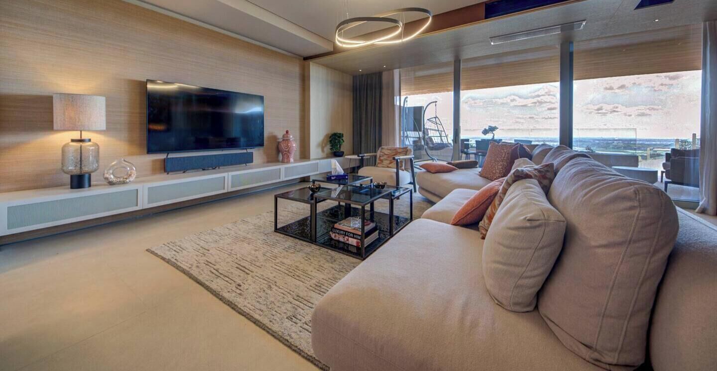 Un salon moderne doté d’un grand téléviseur à écran plat, d’un canapé, d’une table basse et offrant une vue sur la ville.