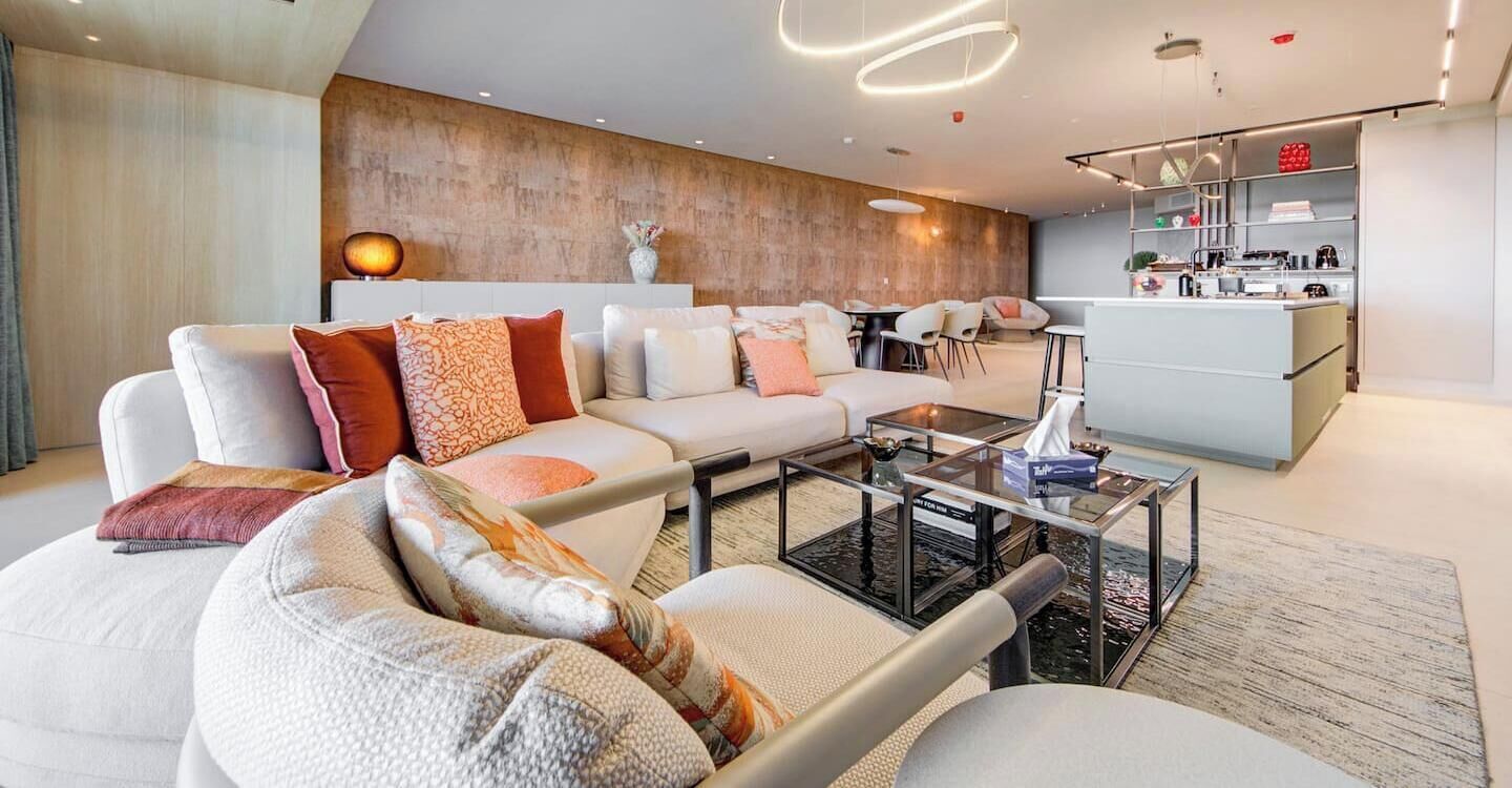 A modern living room with a sofa set, a coffee table, and a kitchen area with a bar.