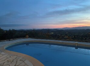 A swimming pool with a stone border, surrounded by a fence, and overlooking a distant cityscape during twilight. - "Moo Graugh Hoo" Villa (Châteauneuf-Grasse)