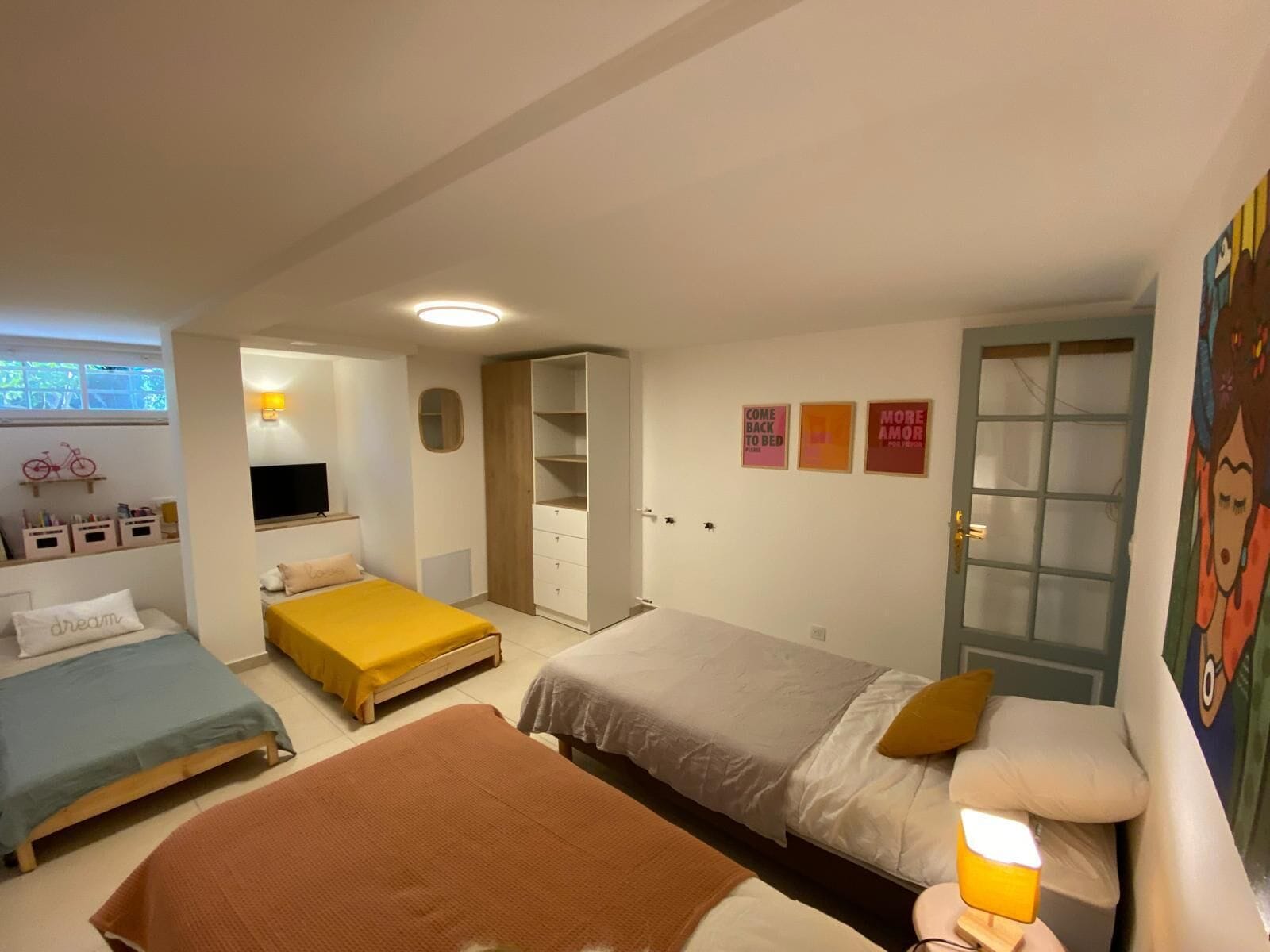 Ein Schlafzimmer mit zwei Betten, einem Kleiderschrank, einem Fernseher und einer Glastür.