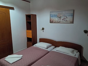 A bedroom with two beds, a wooden wardrobe, and a painting on the wall. - Krista House is a unique family home in a perfect location for a beach holiday. (Agios Giordios)