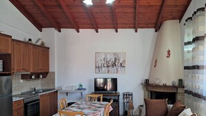 Eine Küche mit Holzausstattung, einem Esstisch mit Stühlen, einem Fernseher und einem Kamin.
