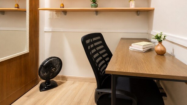 A room with wooden cabinets, a desk, a chair, a small plant, and a fan. - Comfort in Ipanema Near the Beach (Rio de Janeiro)