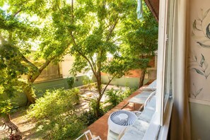 A room with a view of a garden, a window with a curtain, and a fan on the windowsill. - Comfort in Ipanema Near the Beach (Rio de Janeiro)