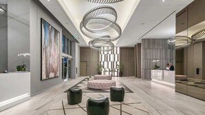 Eine moderne Lobby mit einer zentralen Sitzgruppe, einem Empfangsbereich und einem großen abstrakten Gemälde an der Wand.
