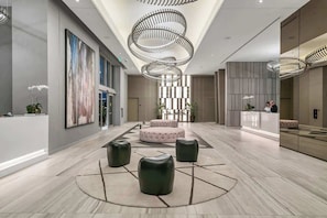 A modern lobby with a central seating area, a reception desk, and a large abstract painting on the wall. - 2BR unit in Hollywood w Breathtaking View (Hollywood)