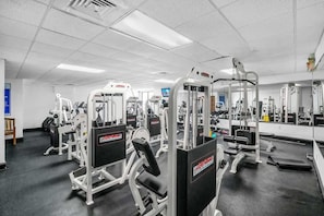 A gym with various exercise machines, mirrors, and a black floor. - Newly renovated 2BR Beachfront (Hollywood)