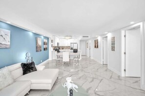 A modern interior with a white sofa, a dining area, and a kitchen. - Bright & Renovated 2BR by the Ocean (Hollywood)