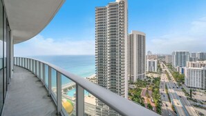 Un immeuble de grande hauteur doté d’un balcon incurvé, offrant une vue sur le paysage urbain et l’océan.