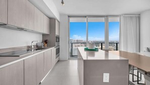 Une cuisine moderne dotée d’une grande fenêtre, d’un coin repas et offrant une vue sur le paysage urbain.