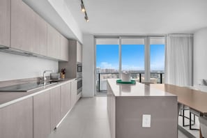 A modern kitchen with a large window, a dining area, and a view of the cityscape. - Luxury Ocean View 2 BR unit (Hollywood)
