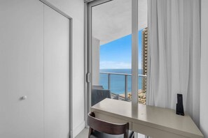 A room with a view of the sea, a balcony with a railing, a desk with a chair, and a window with curtains. - Luxury Ocean View 2 BR unit (Hollywood)
