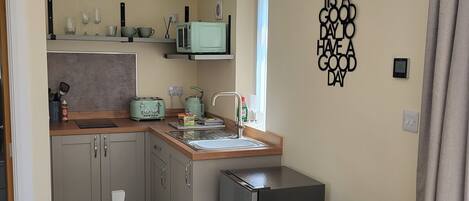 A compact kitchen with a wooden table and chairs, a microwave, and a toaster.
