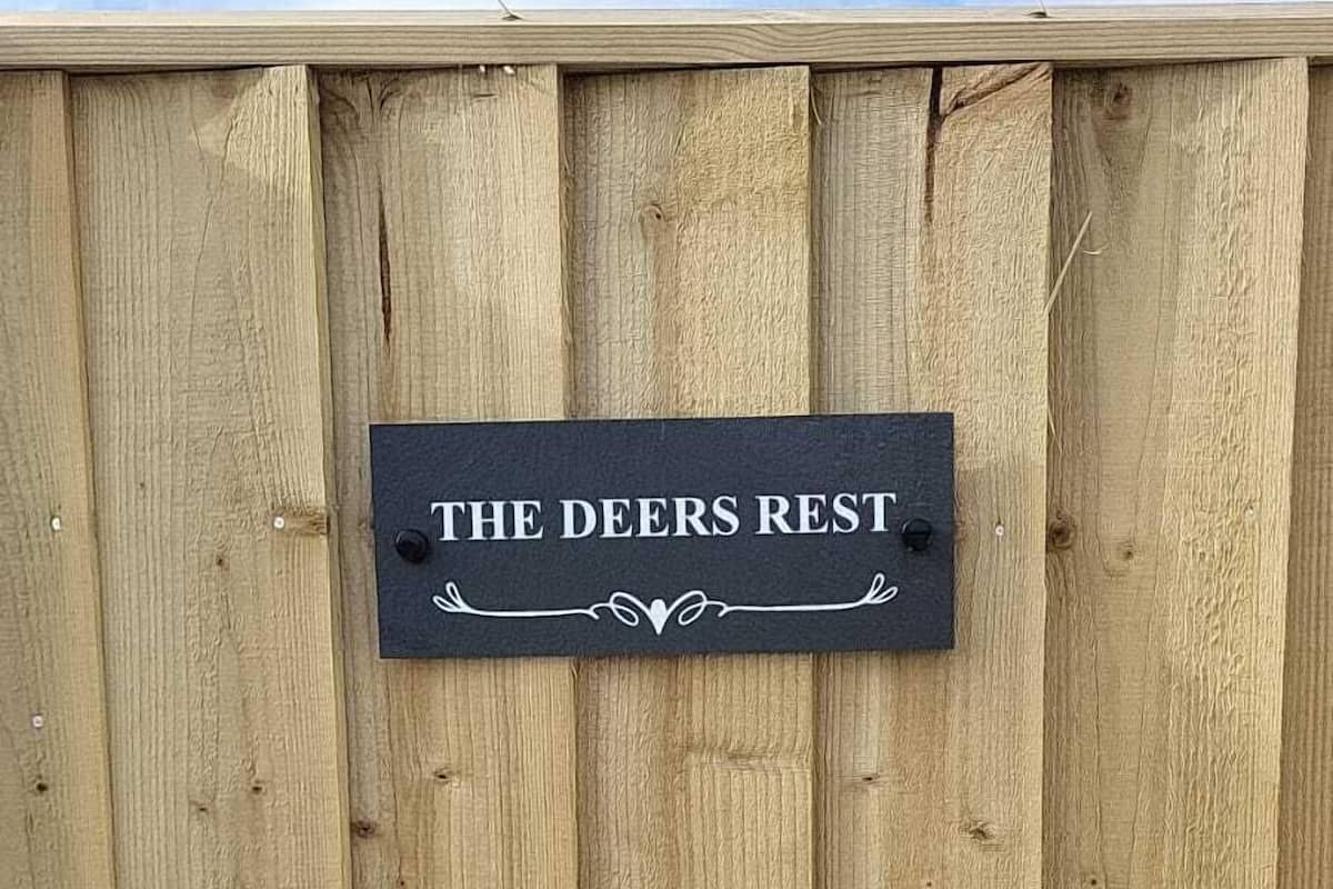 Una cerca de madera con un letrero que dice 'THE DEERS REST'.