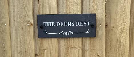 A wooden fence with a sign that reads 'THE DEERS REST.'