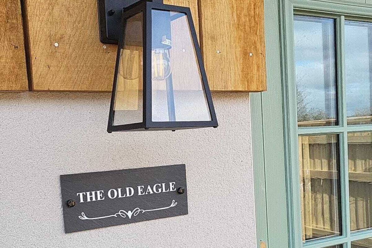Un letrero en la pared que dice 'THE OLD EAGLE' con una lámpara de estilo farol colgando encima.