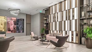 Un hall d’entrée moderne avec un canapé, des fauteuils, une table basse, un mur décoratif et un lustre.