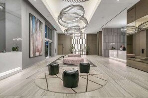 Eine geräumige Lobby mit einer zentralen Sitzecke, einem Empfangsbereich und modernen Leuchten.