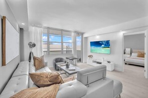 A modern living room with a sofa, a coffee table, and a TV. - Beautiful renovated 2BR unit ocean (Hollywood)