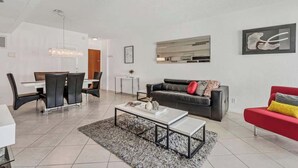 Un salon moderne comprenant un coin repas, un canapé et un divan rouge, ainsi qu’une table basse.