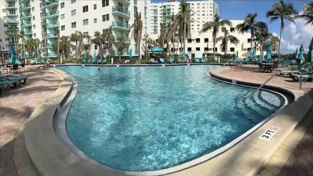 Une piscine entourée de chaises longues et de palmiers, avec une indication de profondeur de 3 pieds.