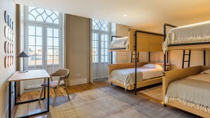 Une chambre avec des lits superposés, un bureau, une chaise et de grandes fenêtres.