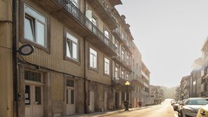 Un immeuble à plusieurs étages doté de balcons, une rue devant et des voitures garées.