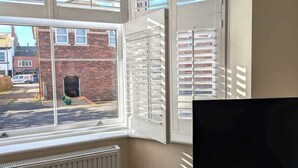Une pièce avec une grande fenêtre, un radiateur et un téléviseur.